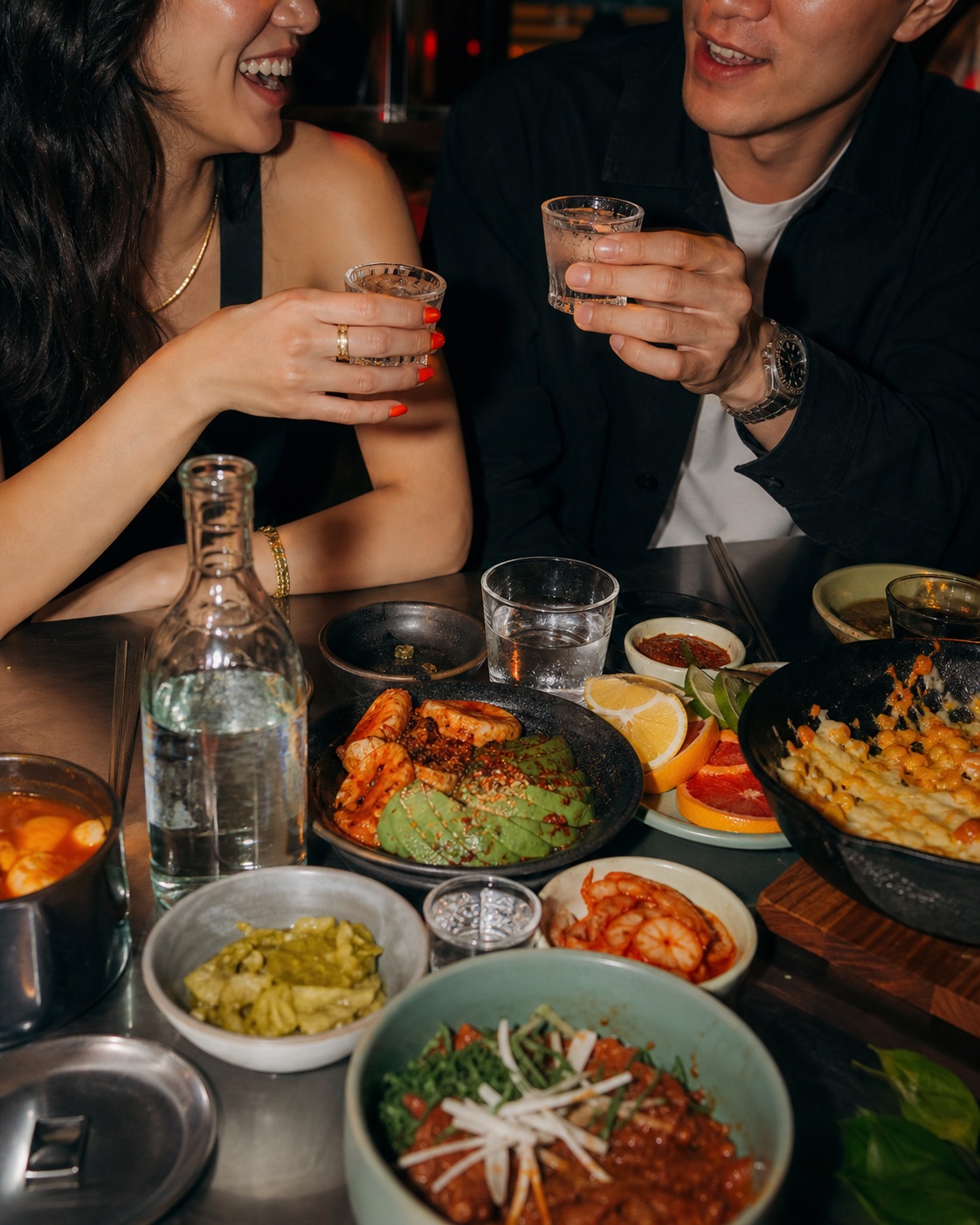 Friends sharing small glasses of soju over Korean food