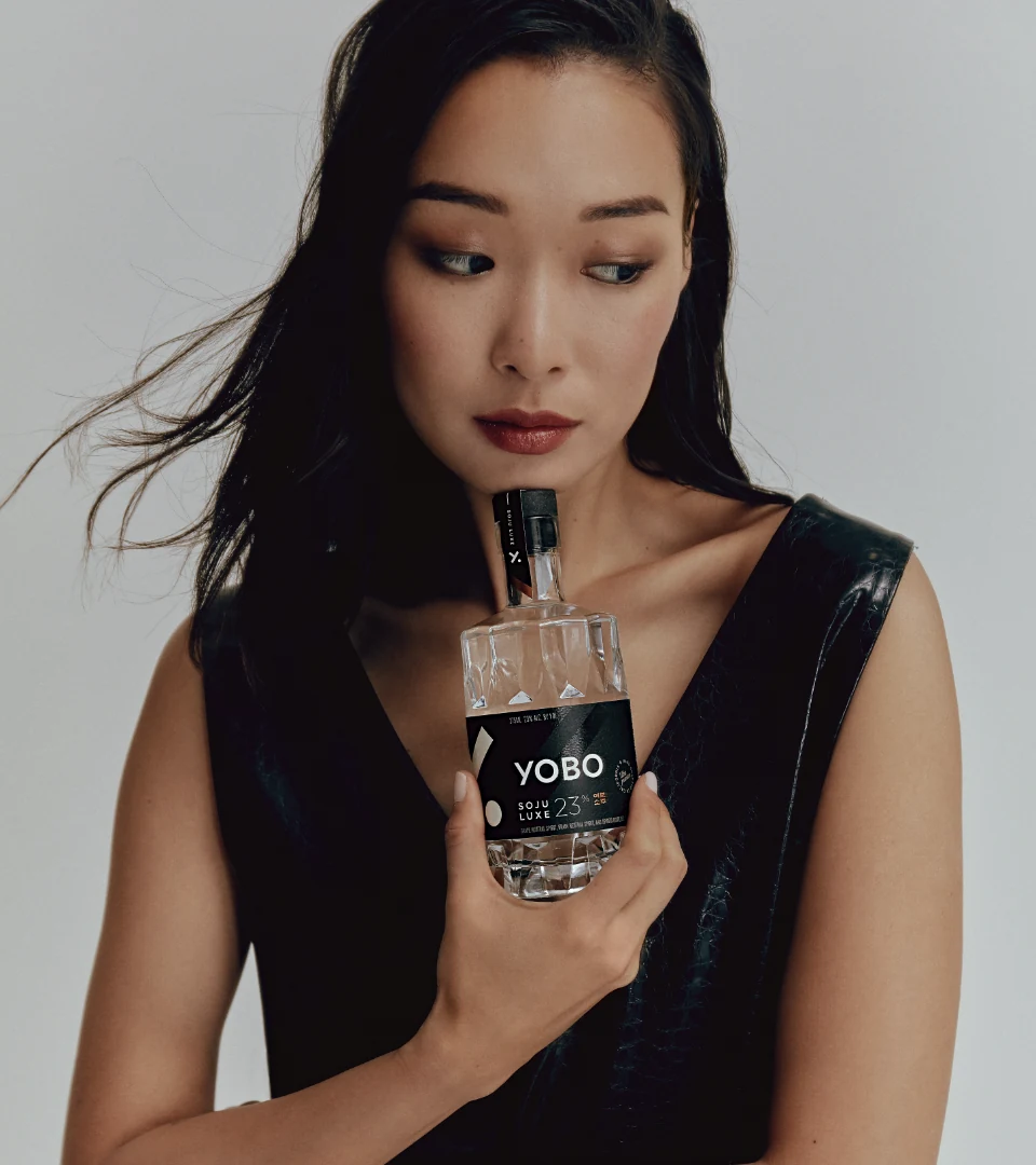 A model holding a bottle of YOBO Soju Luxe